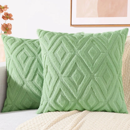 Coussins décoratifs en velours doux de couleur verte avec un motif géométrique, posés sur un canapé clair
