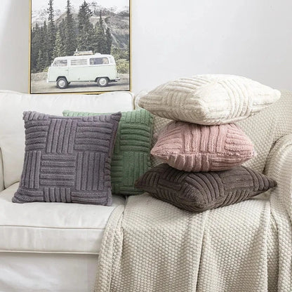 Coussins décoratifs aux textures variées, couleurs douces et motifs en relief, disposés sur un canapé beige