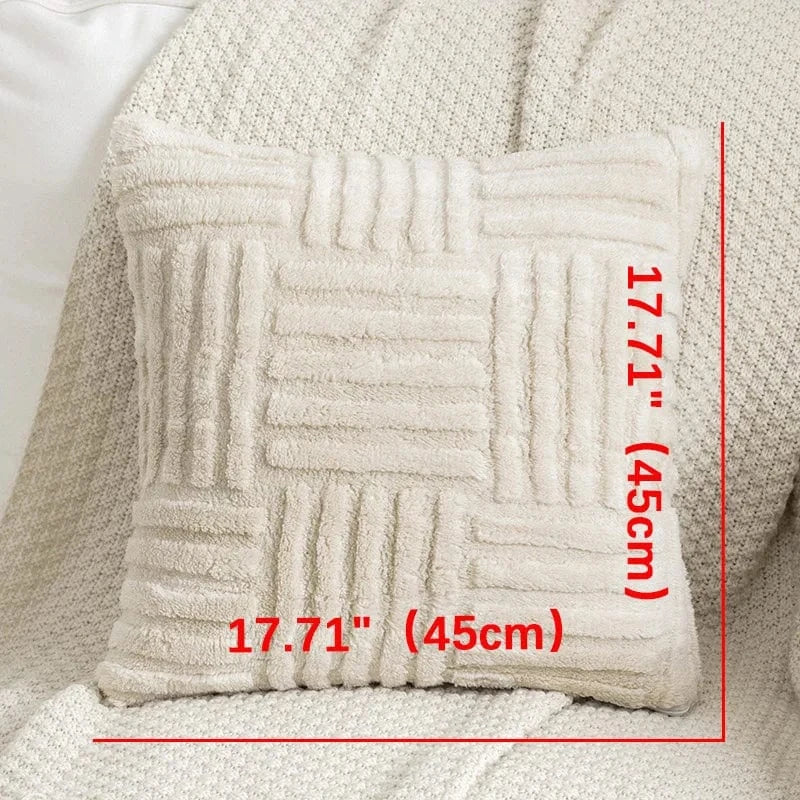Coussin décoratif en fausse fourrure crème, avec un motif texturé, posé sur un canapé beige