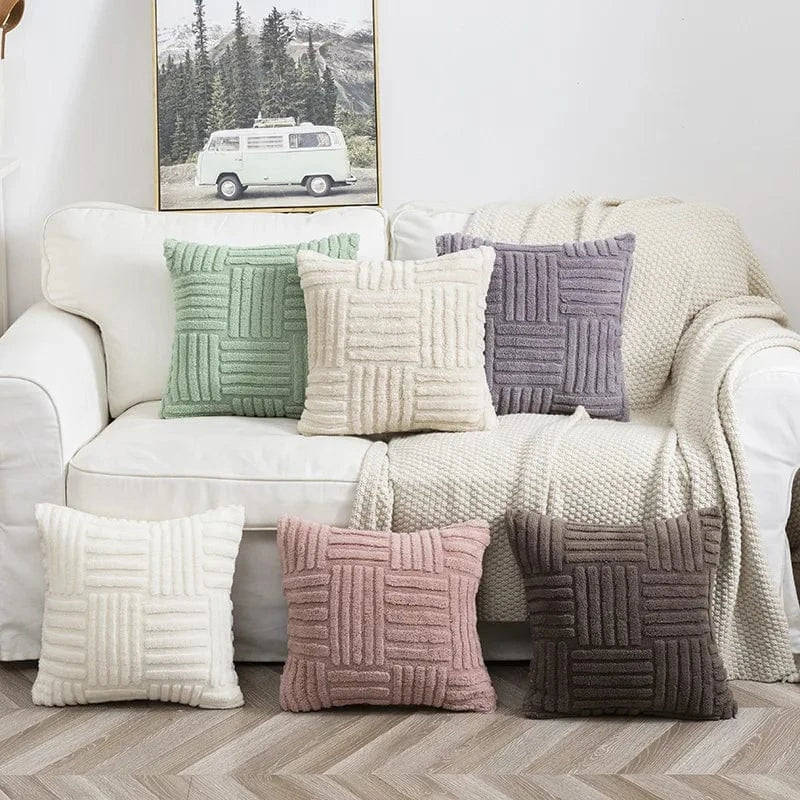 Coussins décoratifs aux couleurs pastel et textures douces, disposés sur un canapé blanc dans un salon cocooning