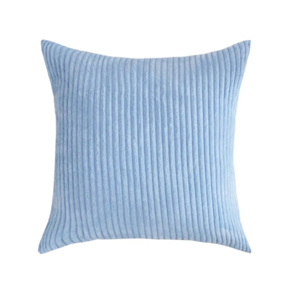 Coussin déco en velours côtelé bleu clair, avec des rayures, posé sur un canapé moderne