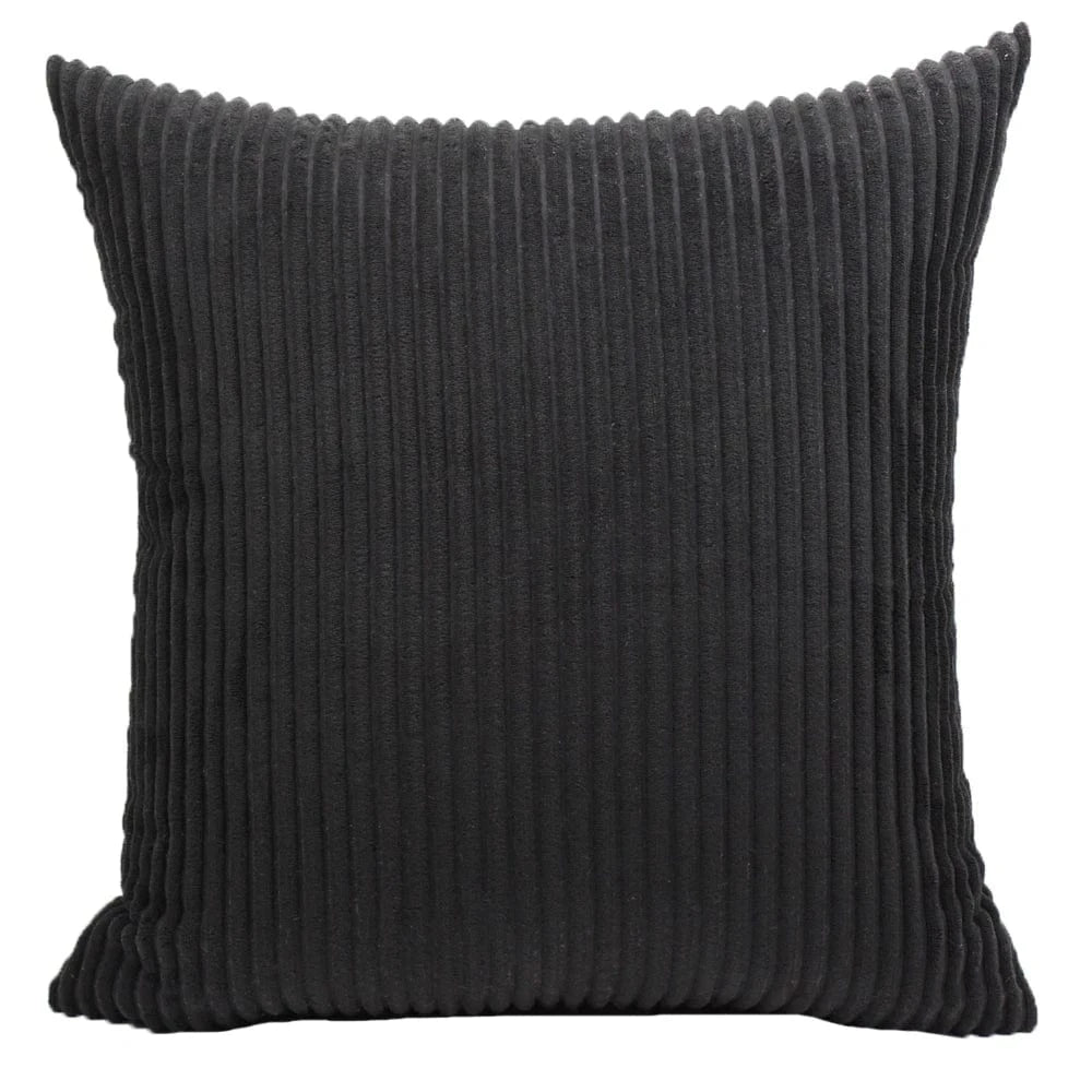 Coussin déco en velours côtelé noir, au design intemporel, posé sur un canapé moderne