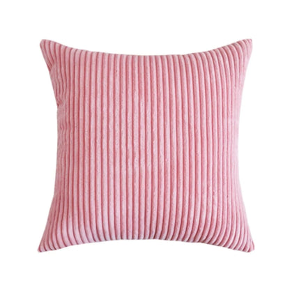 Coussin décoratif en velours côtelé rose, aux rayures élégantes, posé sur un canapé moderne