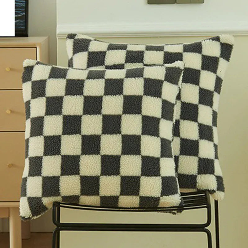 Coussins décoratifs à motifs carreaux noirs et blancs, posés sur une chaise dans un salon moderne
