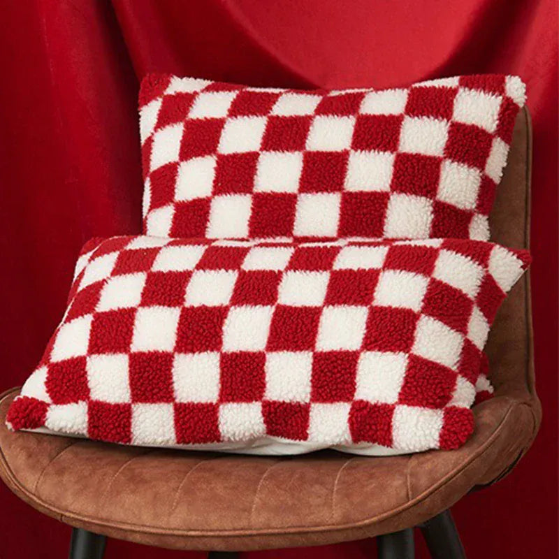 Coussins décoratifs à motifs carreaux rouges et blancs, posés sur une chaise en cuir dans un salon chaleureux