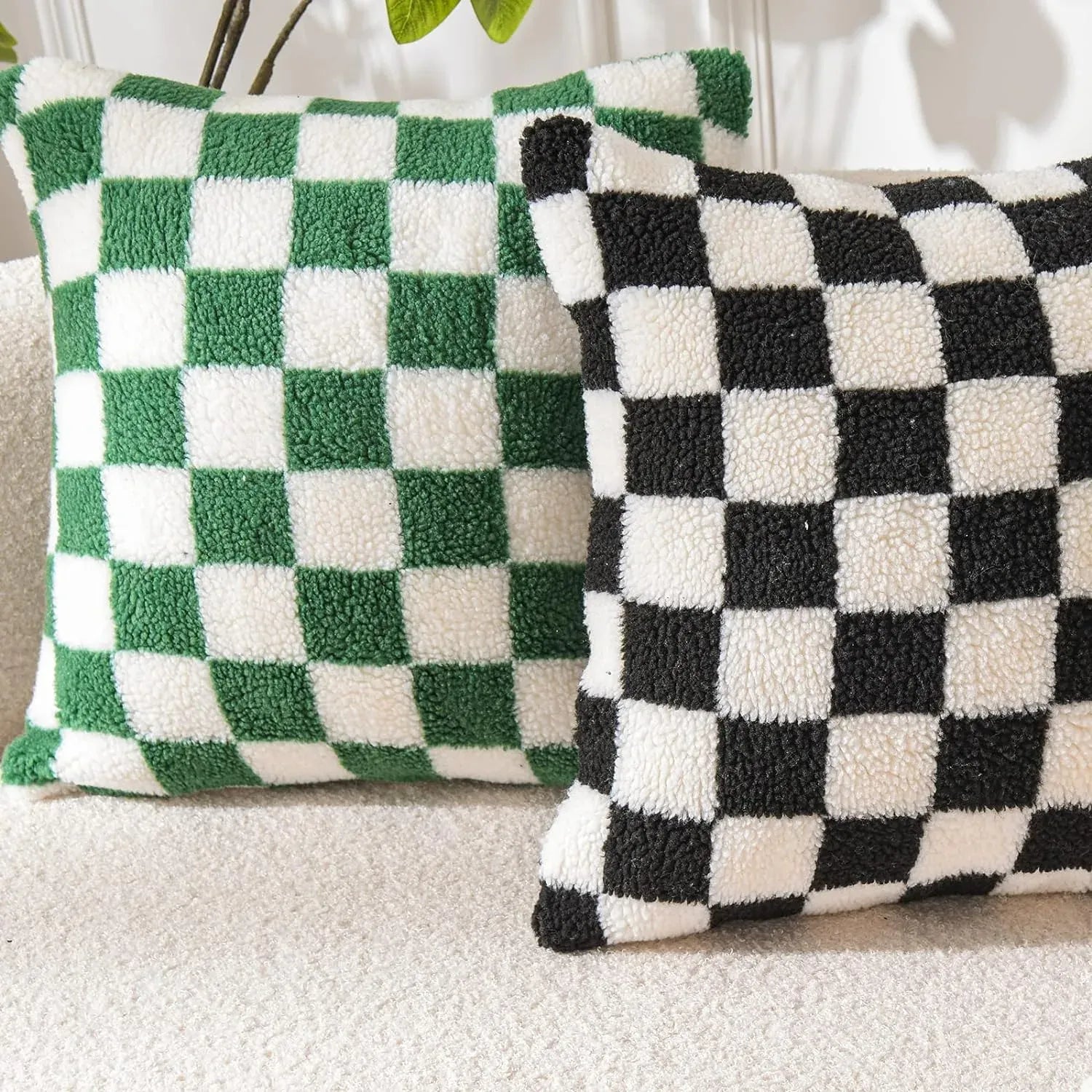 Coussins décoratifs à motifs à carreaux verts et noirs sur un canapé beige, ajoutant une touche moderne au salon