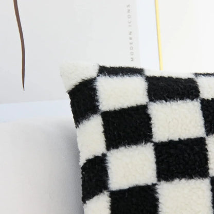 Coussin décoratif à motifs carreaux noir et blanc en tissu pelucheux, posé sur un canapé moderne