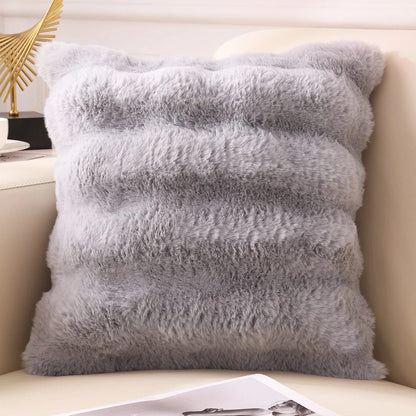 Coussin décoratif en fausse fourrure grise, posé sur un canapé, créant une ambiance cocooning et chaleureuse