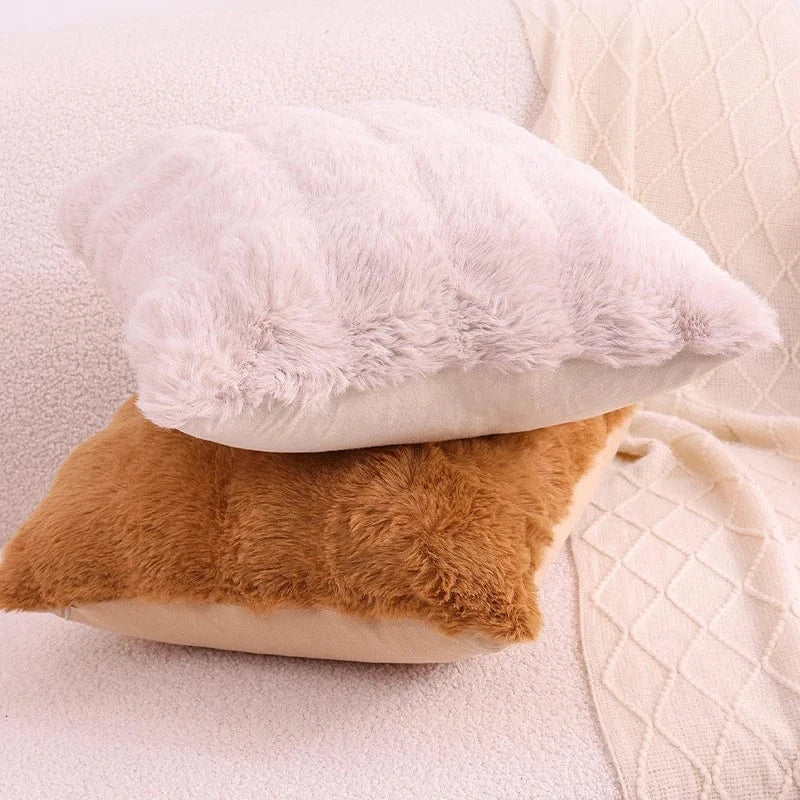 Coussins décoratifs en fausse fourrure beige et marron posés sur un canapé, créant une ambiance cocooning