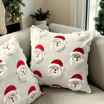 Housse de coussin décoratif blanche avec motifs de Père Noël, posée sur un canapé gris