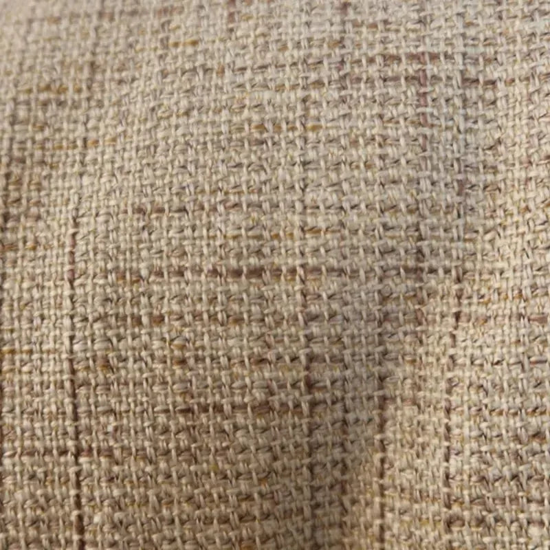 Housse de coussin en tissu beige texturé avec pompons, décorant un canapé moderne dans un salon chaleureux
