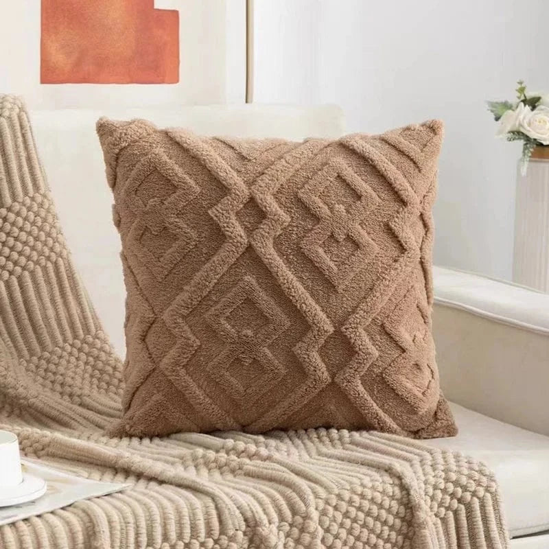 Coussin décoratif en velours beige avec motifs géométriques, posé sur un canapé aux teintes neutres
