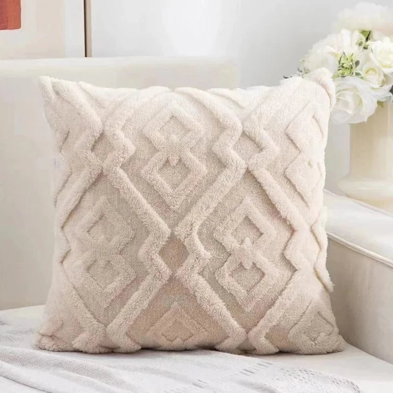 Coussin décoratif beige avec motif géométrique en velours, posé sur un canapé dans un salon lumineux
