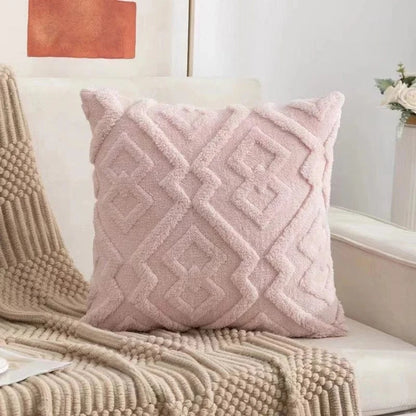 Coussin décoratif rose avec motifs géométriques, posé sur un canapé beige, ajoutant une touche de douceur au salon