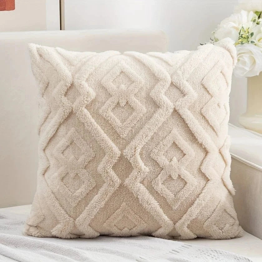 Coussin décoratif beige à motifs géométriques, posé sur un canapé, offrant une texture douce et veloutée