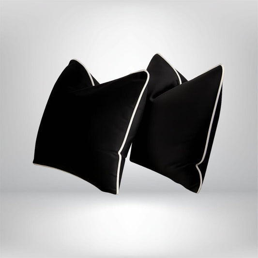 Coussins décoratifs noirs avec bordure blanche, posés sur un fond neutre, apportant une touche élégante à votre intérieur