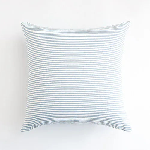 Housse de coussin bleu ciel à rayures, posée sur un canapé moderne, ajoutant une touche décorative
