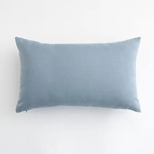 Housse de coussin bleu ciel en lin, posée sur un canapé moderne, apportant une touche de douceur à la décoration