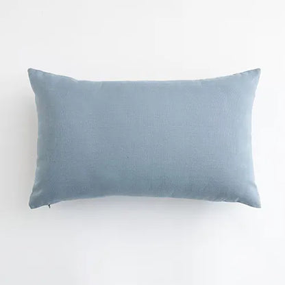Housse de coussin bleu ciel en lin, posée sur un canapé moderne, apportant une touche de douceur à la décoration
