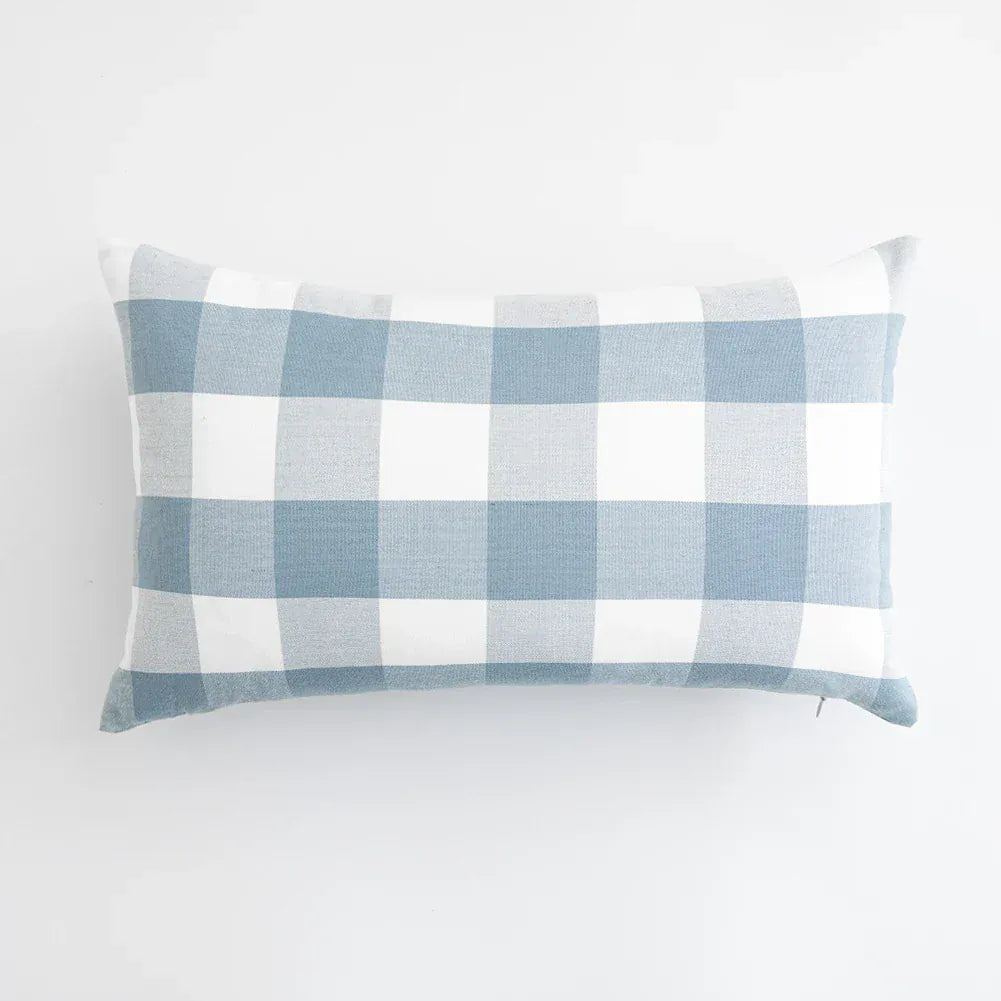 Housse de coussin à motifs carreaux bleu ciel et blanc, posée sur un fond neutre