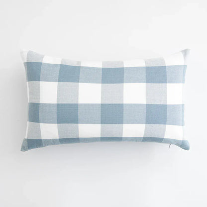 Housse de coussin à motifs carreaux bleu ciel et blanc, posée sur un fond neutre