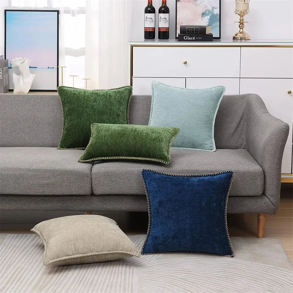 Coussins décoratifs de différentes couleurs sur un canapé gris, incluant des textures douces et des bordures contrastantes