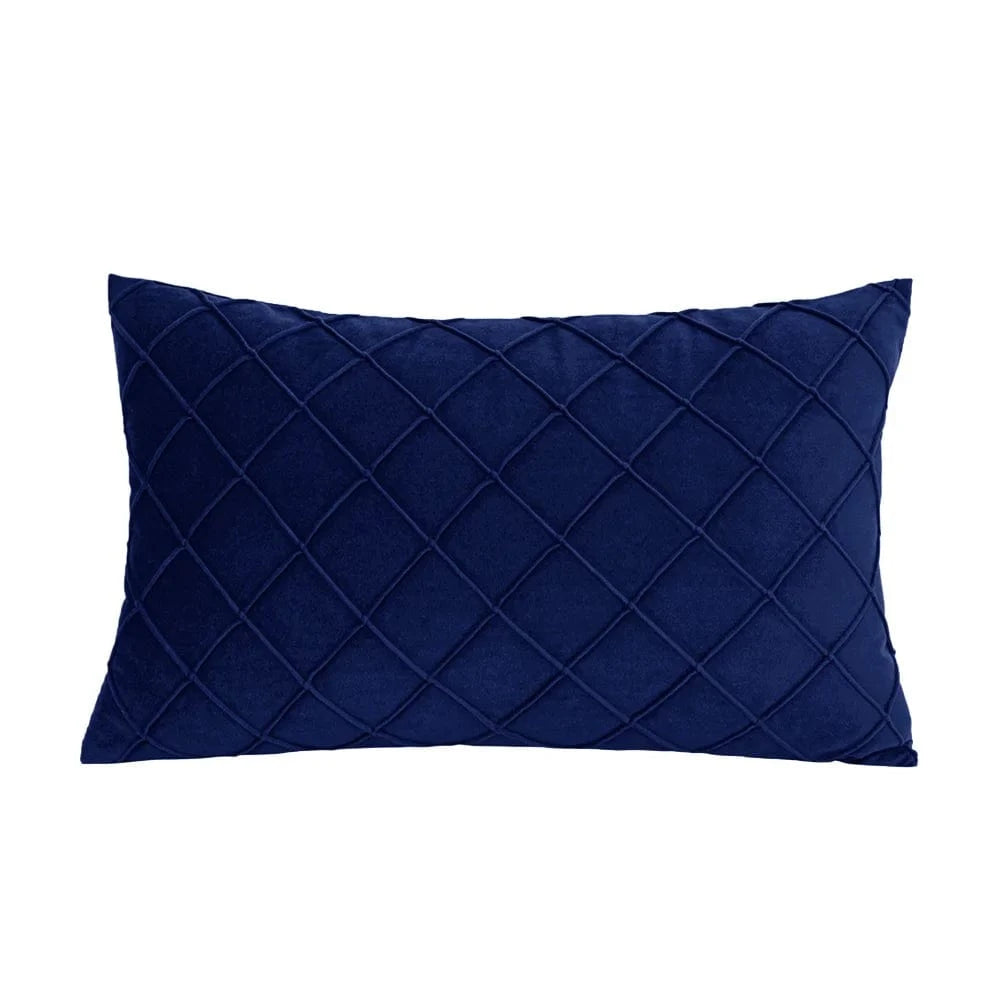 Coussin décoratif bleu nuit en velours avec motif matelassé, posé sur un canapé moderne