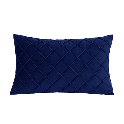 Coussin décoratif bleu nuit en velours avec motif matelassé, posé sur un canapé moderne