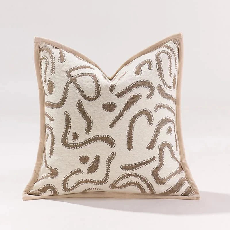 Coussin décoratif beige avec motifs ondulés marron, posé sur un fond neutre, idéal pour un canapé moderne
