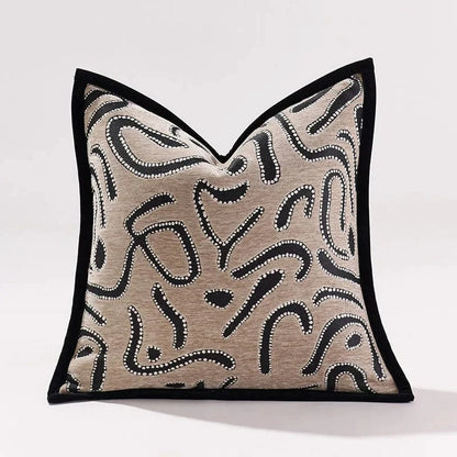 Coussin décoratif avec motif abstrait noir sur fond beige, posé sur un canapé moderne dans un salon élégant