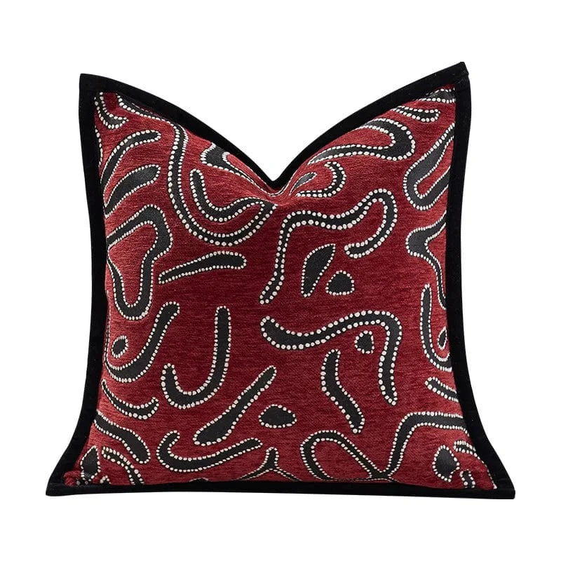 Coussin décoratif rouge avec motifs abstraits noirs et blancs, posé sur un canapé élégant dans un salon moderne