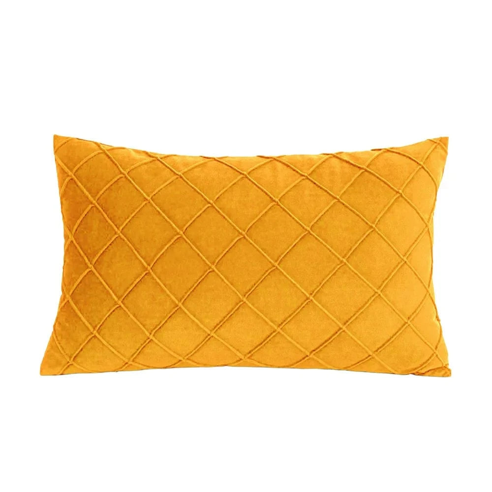 Coussin décoratif rectangulaire en velours jaune avec un motif losange, posé sur un canapé moderne