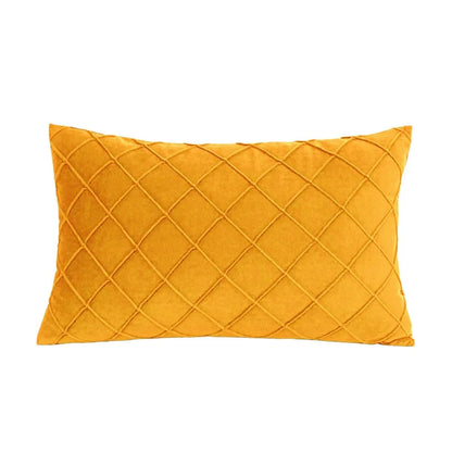 Coussin décoratif rectangulaire en velours jaune avec un motif losange, posé sur un canapé moderne