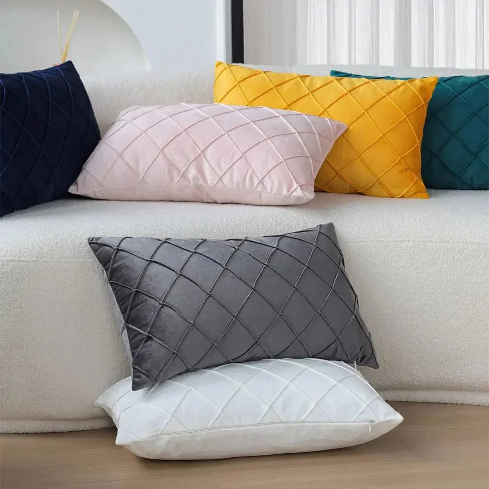 Coussins décoratifs de couleurs variées, en velours, avec motifs en losanges, posés sur un canapé blanc