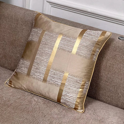 Coussin décoratif aux reflets dorés et motifs texturés, posé sur un canapé beige élégant