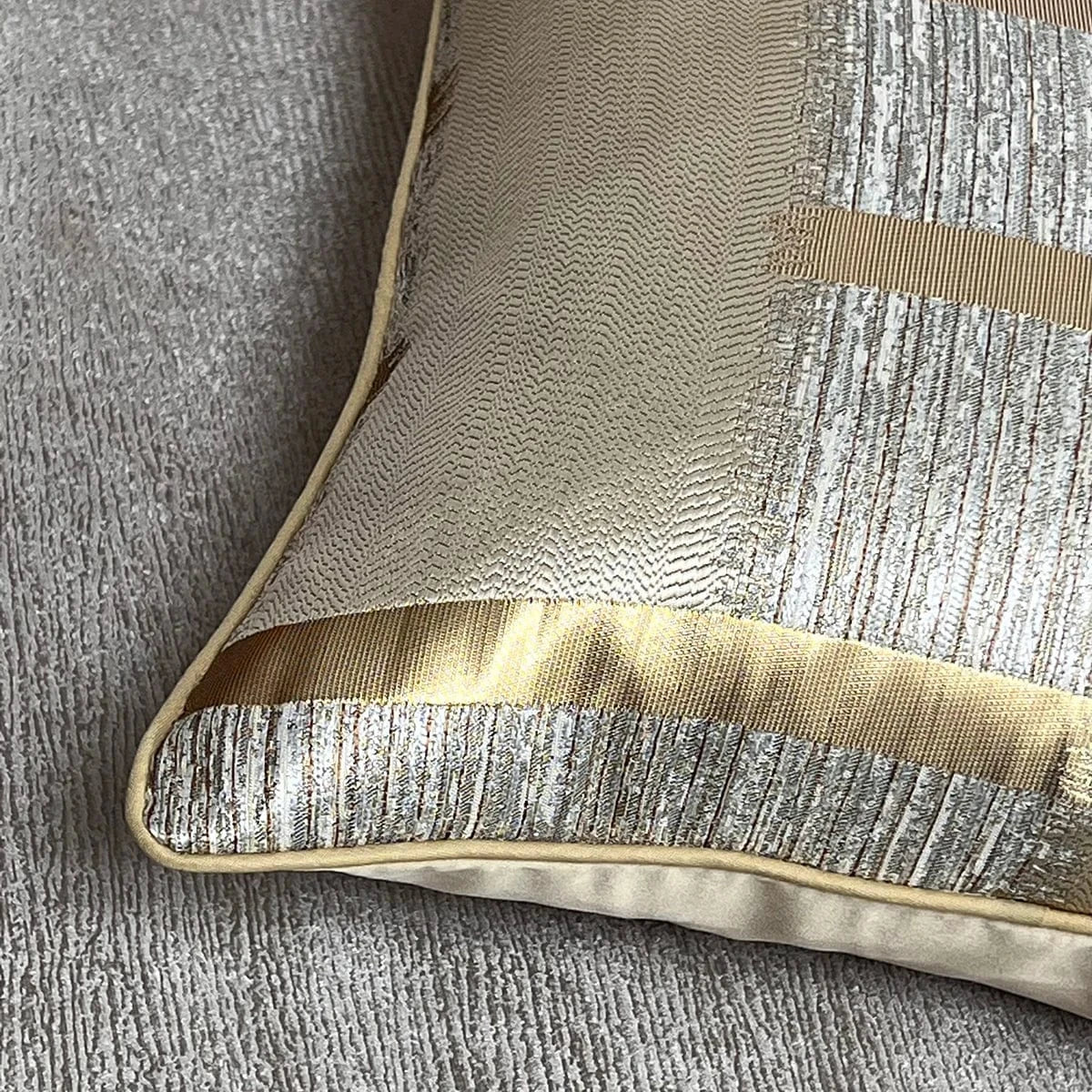 Coussin décoratif aux reflets dorés et argentés, posé sur un tissu gris, ajoutant une touche élégante à votre intérieur