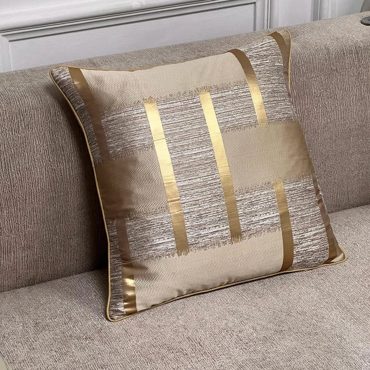 Coussin décoratif aux reflets dorés et motifs texturés, posé sur un canapé beige élégant