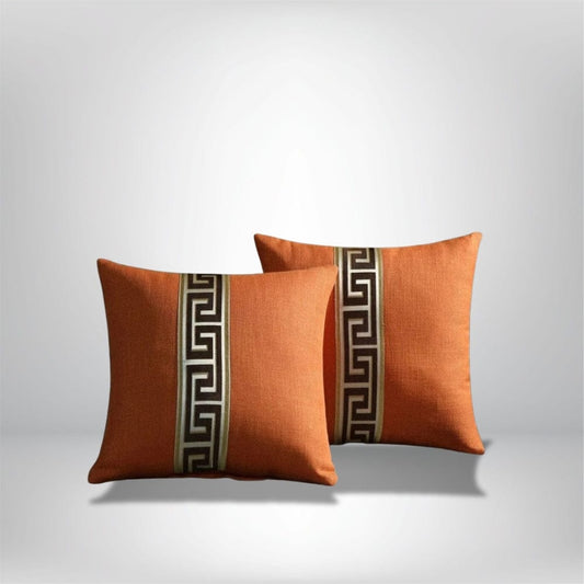 Coussins décoratifs orange avec motif géométrique sur un canapé moderne, ajoutant une touche élégante au salon