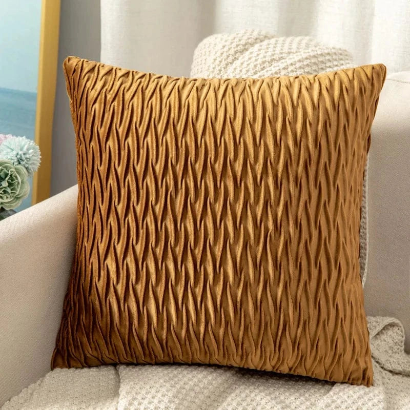 Coussin décoratif en velours doré avec un motif texturé, posé sur un canapé moderne et élégant