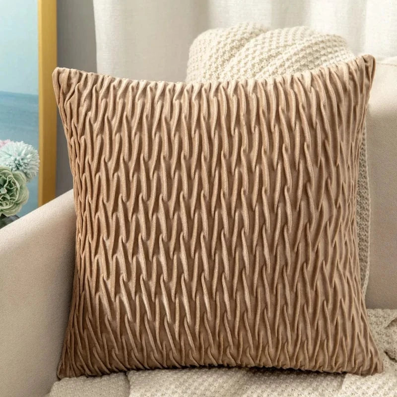 Coussin décoratif en velours beige avec un motif ondulé, posé sur un canapé dans un salon moderne