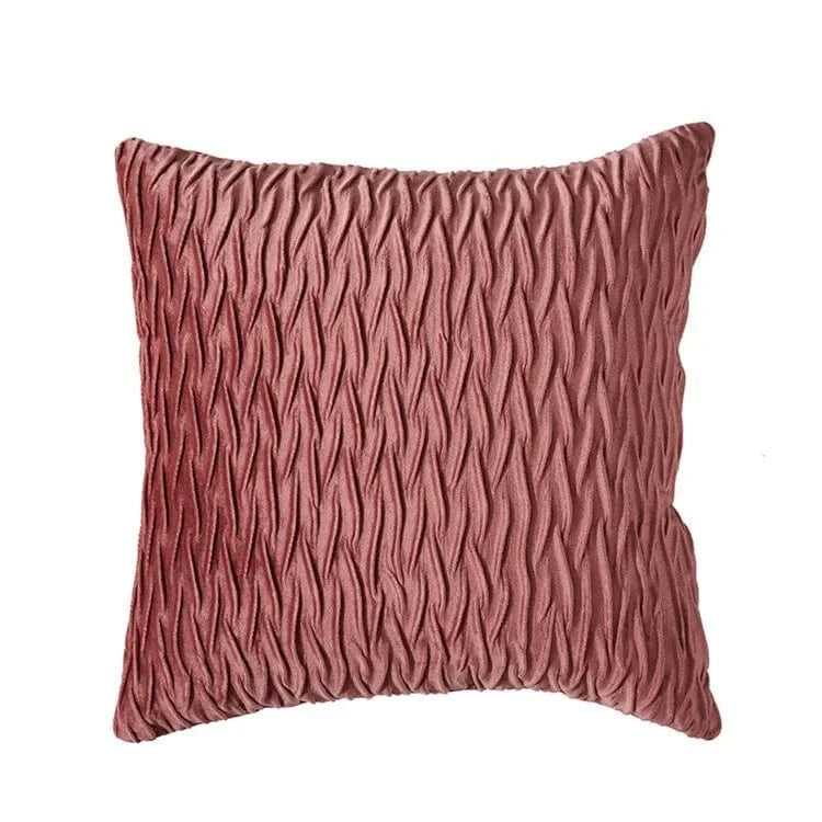 Coussin décoratif en velours rose avec un motif texturé, posé sur un canapé moderne pour une ambiance chic