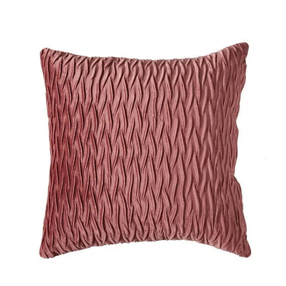 Coussin décoratif en velours rose avec un motif texturé, posé sur un canapé moderne pour une ambiance chic
