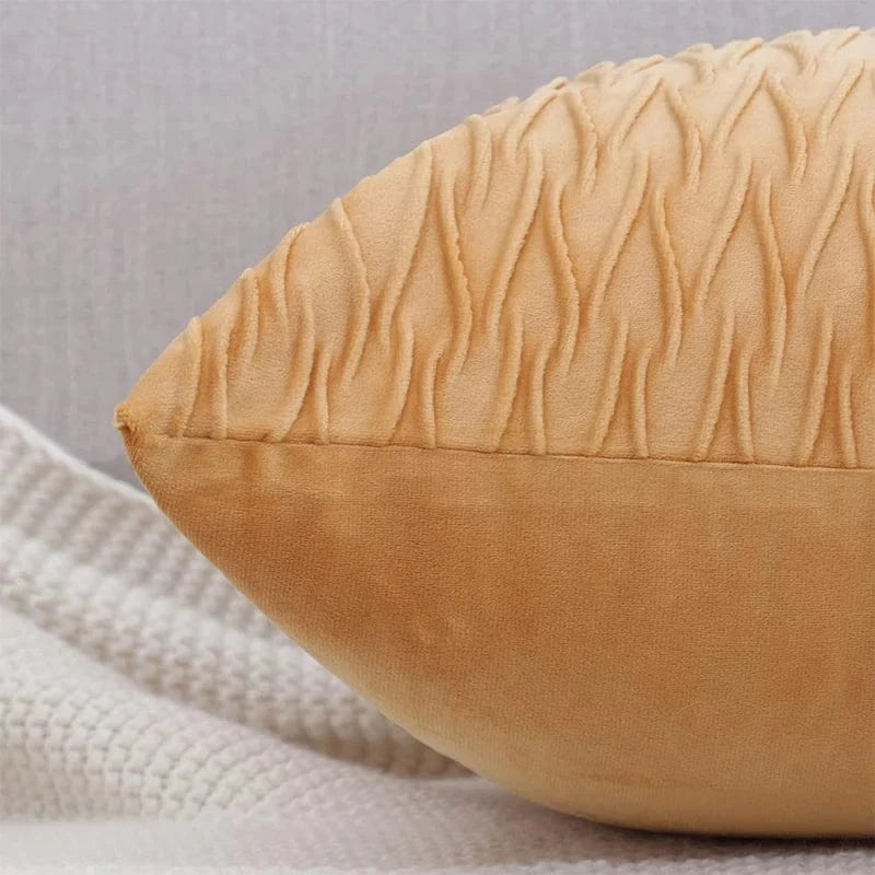 Coussin décoratif en velours beige avec un motif texturé, posé sur un canapé moderne et élégant