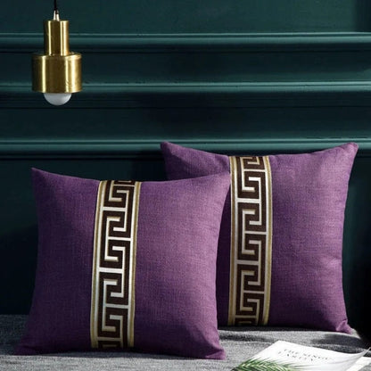 Coussins décoratifs violets avec motif géométrique doré, posés sur un canapé dans un salon élégant