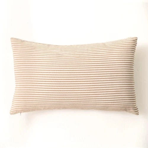 Coussin déco rectangulaire à rayures beiges sur fond clair, posé sur un canapé élégant