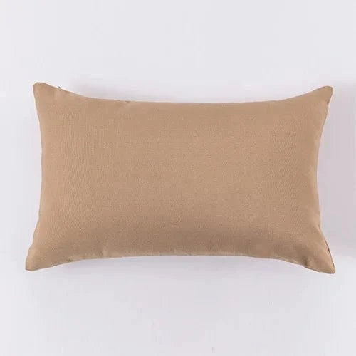 Coussin déco rectangulaire beige en tissu doux, posé sur un fond neutre, idéal pour un fauteuil élégant