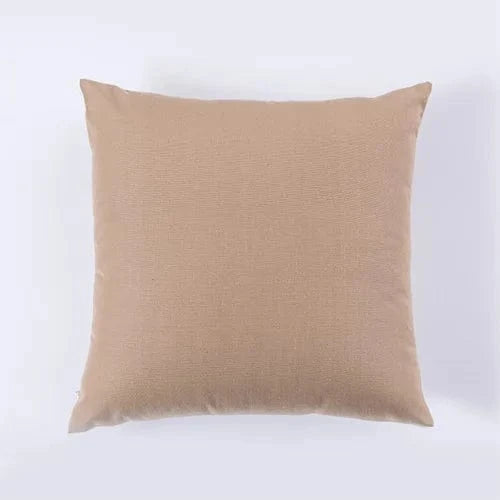 Coussin décoratif beige en tissu texturé, posé sur un fond neutre, idéal pour un fauteuil élégant