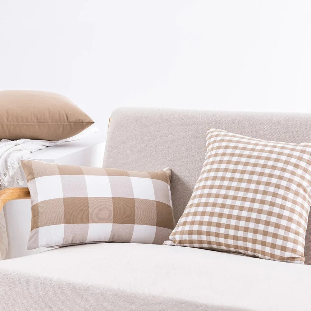 Coussins décoratifs aux motifs vichy beige et blanc, posés sur un canapé élégant et moderne