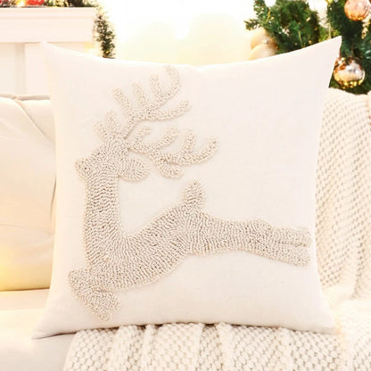 Coussin décoratif blanc avec un motif de renne en relief, posé sur un canapé cosy, parfait pour une ambiance festive