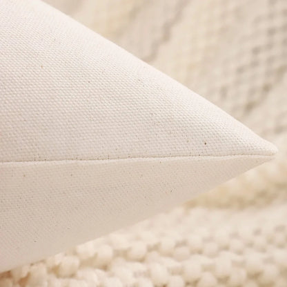 Housse de coussin décoratif blanche en tissu sur un fond de texture douce et chaleureuse, idéale pour un salon cocooning